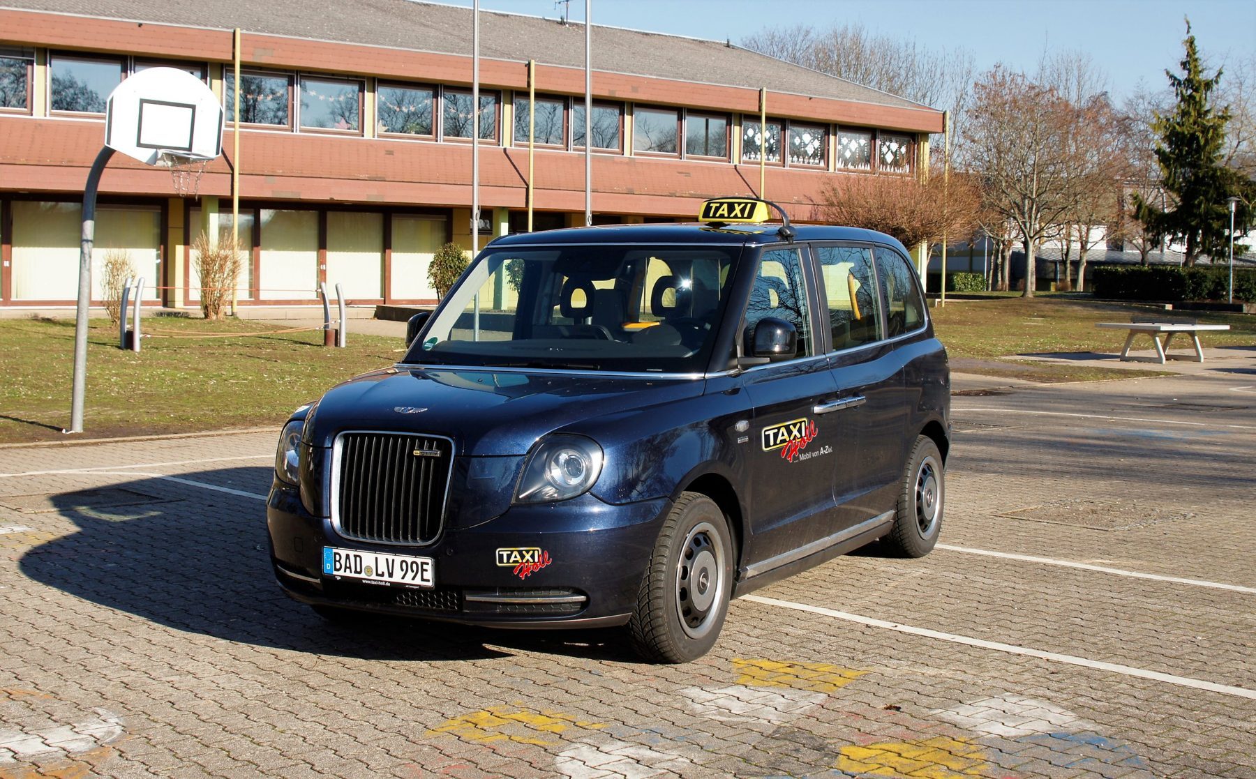 Dunkelblaues London-Taxi mit gelbem Taxischild und Taxi-Holl-Logo