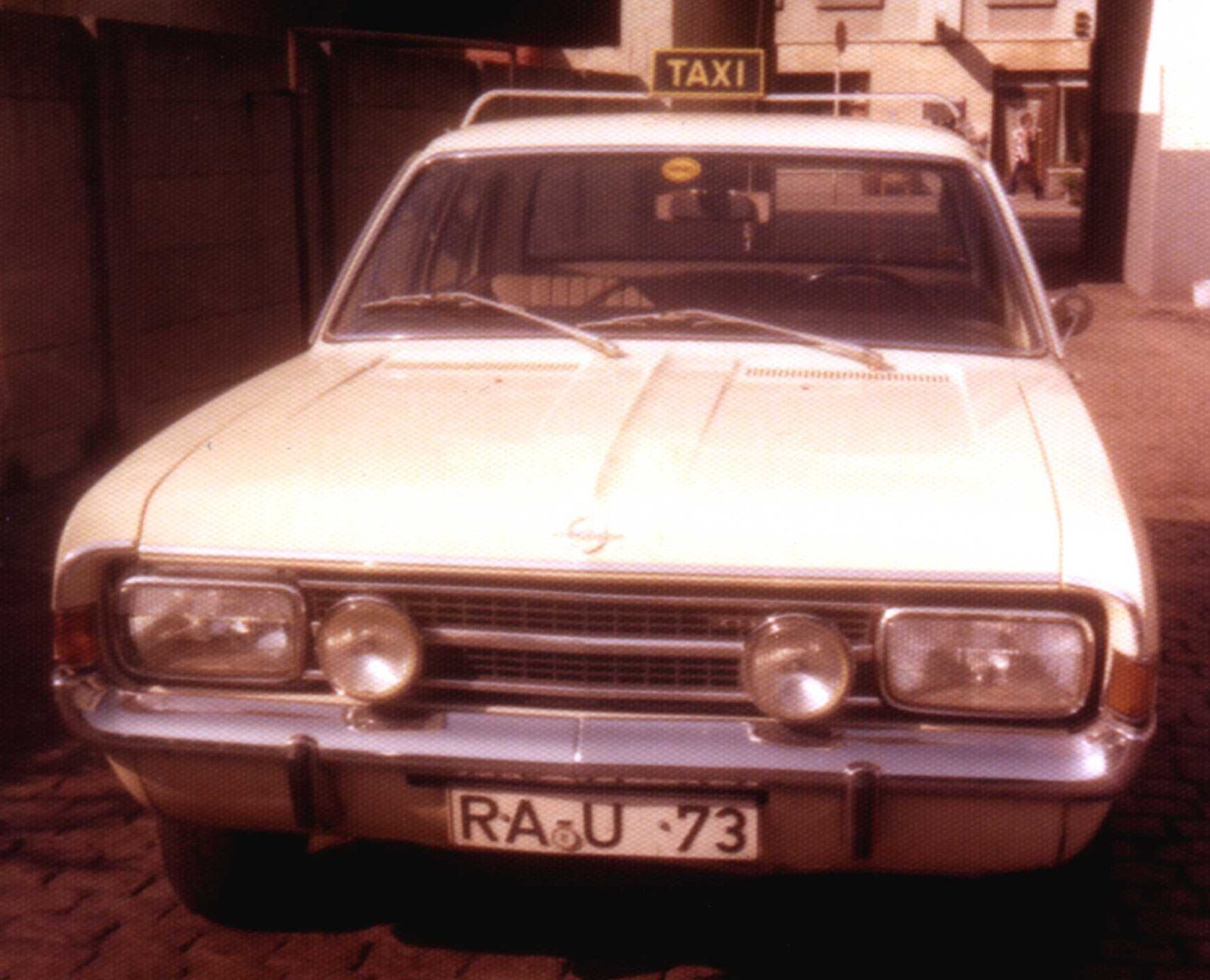 Hellelfenbeinfarbener Opel Rekord mit Taxischild auf dem Dach, Kennzeichen RA-U 73, von vorn fotografiert